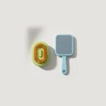 Pack de dos cepillos para mascotas: cepillo con pulverizador y cepillo quitapelos sobre fondo claro